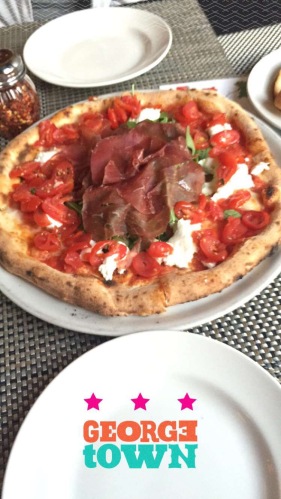 Neapolitan pizza with cherry tomatoes, prosciutto, and arugula.